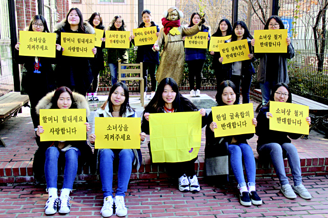 1. 지난 4월 서울 프란치스코교육회관 앞에서 이화여고 ‘주먹도끼’ 학생들이 스스로 기금을 마련해 건립한 소녀상 앞에서 손팻말을 들고 있다. 최화진 기자