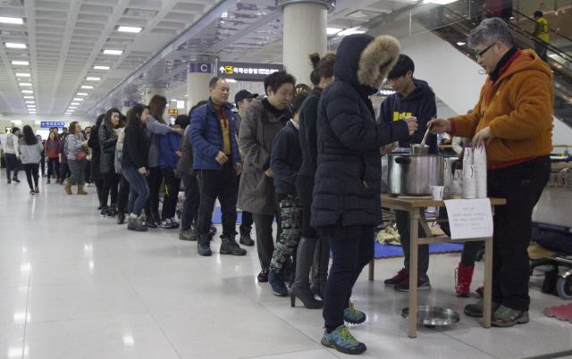 폭설과 강풍으로 항공편 운항이 중단됐던 25일 오전 제주공항에서 승객들이 한 교회가 준비한 주먹밥과 된장국을 받고 있다. 제주/김성광 기자 <A href="mailto:flysg2@hani.co.kr">flysg2@hani.co.kr</A>