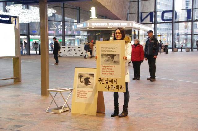 백민주화씨가 27일 오후(현지시각) 네덜란드 로테르담 중앙역에서 1인 시위를 벌이고 있다. 손팻말에는 “국민 앞에서 사과하라”라는 글귀가 쓰여 있다. 백민주화씨 제공