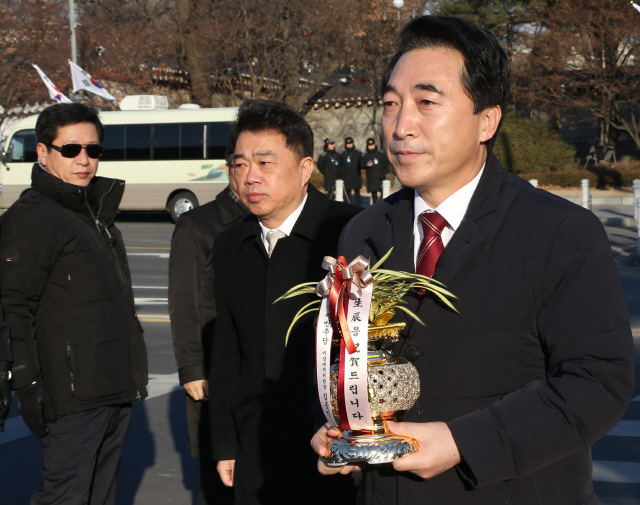 더불어민주당 김종인 비상대책위원장의 비서실장인 박수현 의원이 2일 오후 청와대 분수대광장에서 김 위원장이 박근혜 대통령에게 보내는 생일 축하난을 들고 청와대로 향하고 있다. 
 이정우 선임기자 woo@hani.co.kr