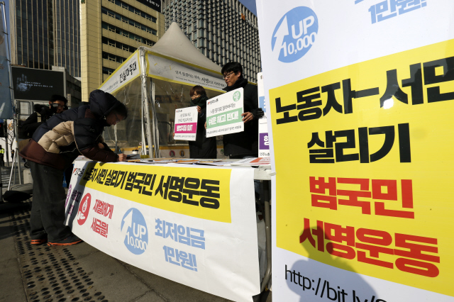 한 시민이 3일 오전 서울 종로구 세종로 광화문광장에서 ‘노동자-서민 살리기 범국민 서명운동’에 동참해 서명을 하고 있다. 민주노총은 이날 기자회견을 열어 “‘쉬운 해고 안 돼! 재벌에게 세금을! 최저임금 1만원!’이라는 노동자 서민 3대 요구를 내걸고 재벌-정부 관제 서명운동에 맞불을 놓는 서명운동을 전개한다”고 밝혔다. 김명진 기자 littleprince@hani.co.kr