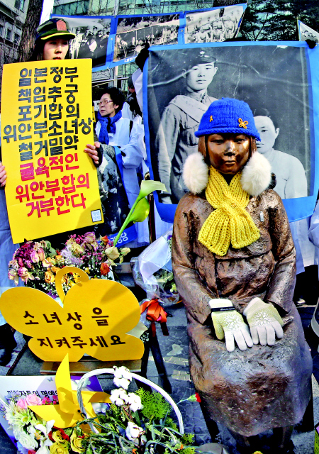 3일 서울 종로구 중학동 주한일본대사관 앞에 있는 ‘소녀상’ 옆에서 한 청년단체 회원이 한·일 정부의 일본군 ‘위안부’ 피해자 문제와 관련한 ‘12·28 합의’를 비판하는 손팻말을 들고 서 있다. 이정용 선임기자 lee312@hani.co.kr