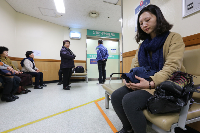 백도라지씨가 2일 아버지 백남기씨 병실 앞에서 아버지가 마지막까지 입고 있었던 옷을 매만지며 아버지의 쾌유를 빌고 있다. 강재훈 선임기자