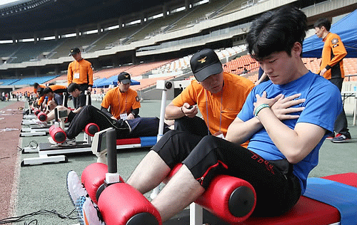 서울 송파구 잠실주경기장에서 열린 소방공무원 체력시험에서 응시자들이 윗몸일으키기를 하고 있다. 2015.5.11. 연합뉴스