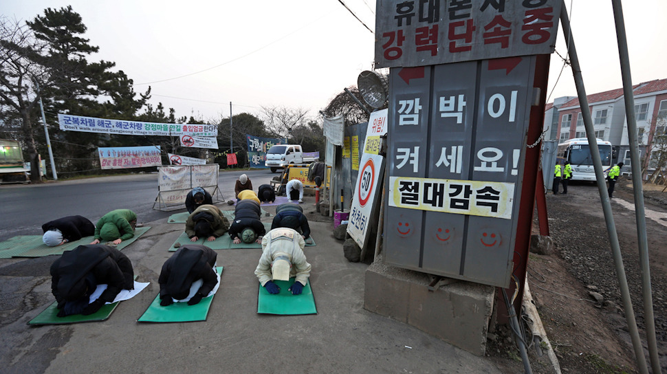 제주 서귀포 강정해군기지 준공식이 열리는 26일 새벽 해군기지 공사장 입구에서 강정마을 주민들과 시민단체 회원들이 ‘생명평화 백배’를 하고 있다. 서귀포/ 이정용 선임기자 lee312@hani.co.kr