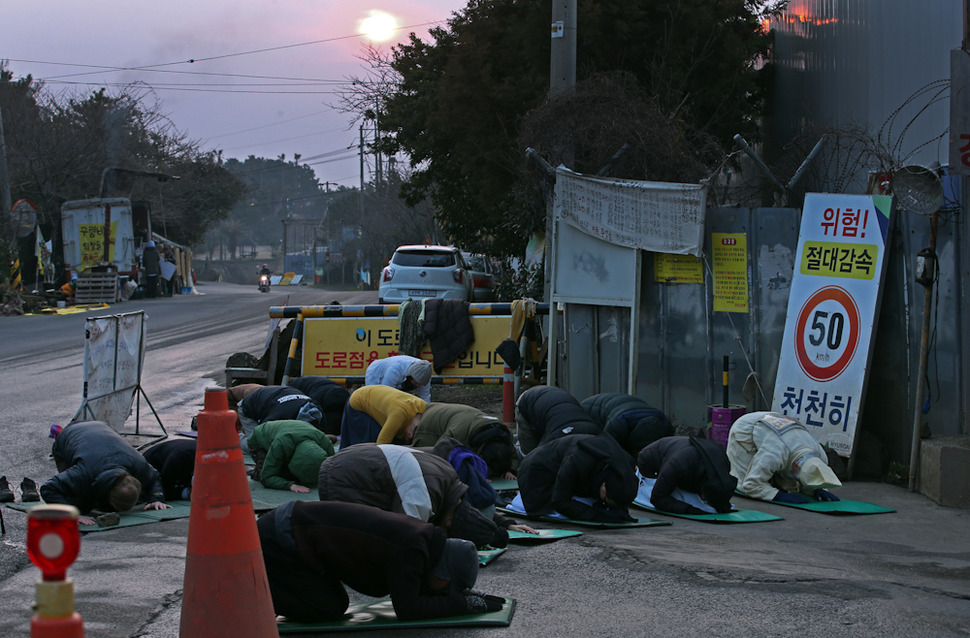 제주 서귀포 강정해군기지 준공식이 열리는 26일 새벽 해군기지 공사장 입구에서 강정마을 주민들과 시민단체 회원들이 ‘생명평화 백배’를 하고 있다. 서귀포/ 이정용 선임기자 lee312@hani.co.kr