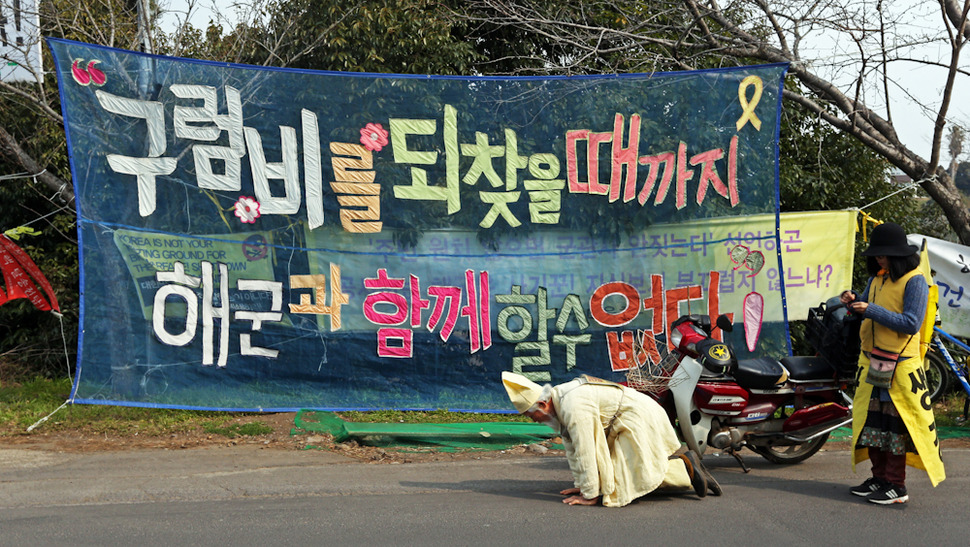 제주 서귀포 강정해군기지 준공식이 열린 26일 해군기지 공사장 입구에서 강정마을 주민들과 시민단체 회원들이 침묵시위를 벌이는 동안 한 주민이 삼보일보를 하고 있다. 서귀포/ 이정용 선임기자 lee312@hani.co.kr