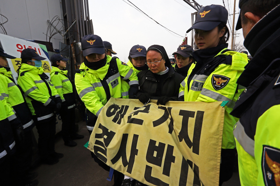 제주 서귀포 강정해군기지 준공식이 열린 26일 해군기지 공사장 입구에서 강정마을 주민들과 시민단체 회원들이 묵상시위를 벌이자 경찰들이 한사람씩 들어서 옮기고 있다. 서귀포/ 이정용 선임기자 lee312@hani.co.kr