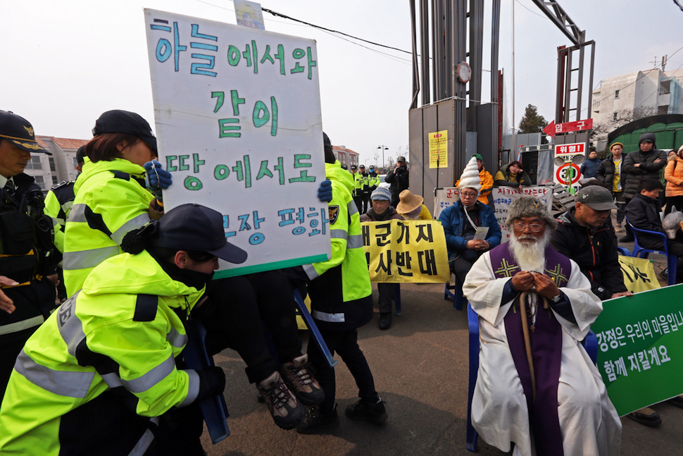 제주 서귀포 강정해군기지 준공식이 열린 26일 해군기지 공사장 입구에서 강정마을 주민들과 시민단체 회원들이 묵상시위를 벌이자 경찰들이 한사람씩 들어서 옮기고 있다. 서귀포/ 이정용 선임기자 lee312@hani.co.kr