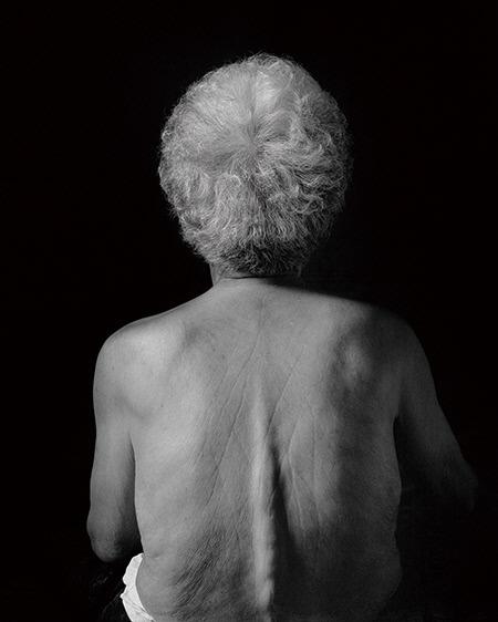 여성사진가 장숙씨의 작품 중 검게 암전된 배경 아래 노년 여성들의 벗은 뒤태를 포착한 작품.