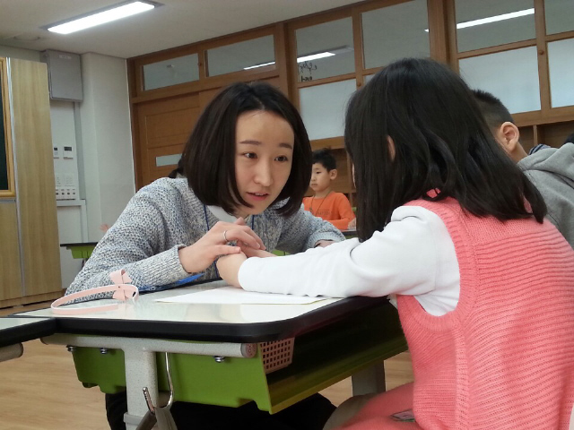 크레파스를 짝꿍과 나눠 쓰려 하지 않는 아이를 설득하고 있는 이지영 교사. 허재현 기자