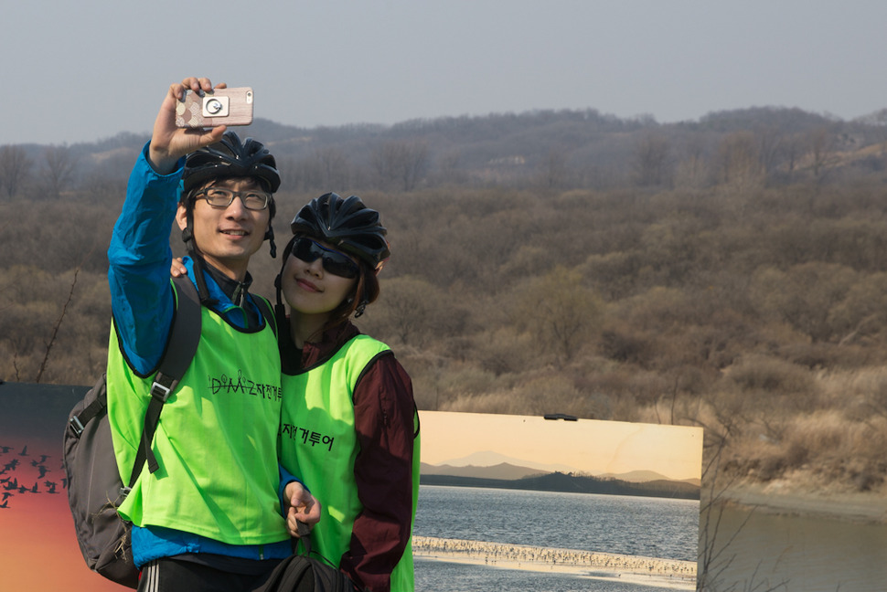 ‘비무장지대(DMZ) 자전거 투어‘가 27일 오후 경기 파주 임진각에서 열려 행사에 참가한 한 연인이 쉬는시간을 이용해 초평도를 배경으로 사진촬영을 하고 있다. 파주/김성광 기자 flysg2@hani.co.kr