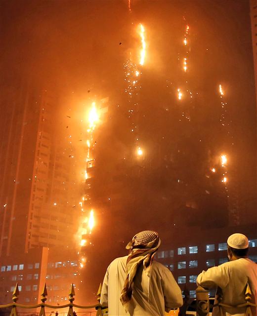  아랍에미리트(UAE) 당국자 두명이 29일 밤 남부 아지만의 한 고층빌딩 밖에서 건물을 뒤덮은 불길을 바라보고 있다. 당국은 구체적인 사상자 수를 밝히지 않았지만 현지 언론들은 인명피해가 없다고 보도했다.   아지만/AP연합뉴스