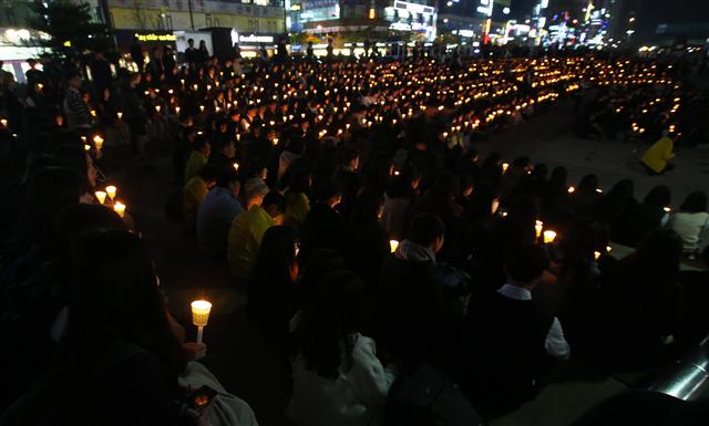 세월호 참사 2주기를 하루 앞둔 15일 오후 경기 안산시 단원구 안산문화광장에서 안산고교학생회장단연합이 연 ‘세월호 참사 희생자 2주기 추모제’에 참석한 학생들이 촛불을 들고 세월호 참사 희생자들을 추모하고 있다.  안산/연합뉴스