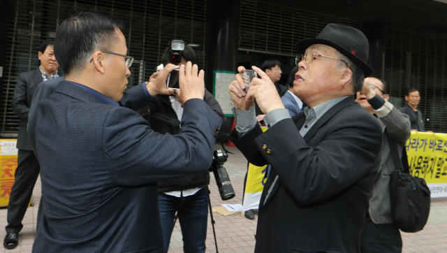  퇴직 경찰관 모임인 민주경우회(무궁화클럽)와 경찰개혁시민행동 회원들이 20일 오전 서울 신당동 대한민국재향경우회 앞에서 재향경우회가 탈북단체 등에 금품을 제공하고 인력을 동원한 사실을 비판하는 기자회견을 여는 동안 재향경우회 관계자(왼쪽)와 한 회견 참가자가 휴대전화로 상대방을 서로 촬영하며 신경전을 벌이고 있다.  김정효 기자 hyopd@hani.co.kr