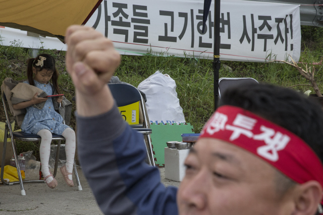 한 어린이가 22일 저녁 경남 고성군 에스티엑스고성조선해양 앞 농성장에서 체불임금 지급 촉구 집회에 참가중인 아버지를 기다리며 휴대전화 화면을 보고 있다.  고성/김성광 기자 flysg2@hani.co.kr