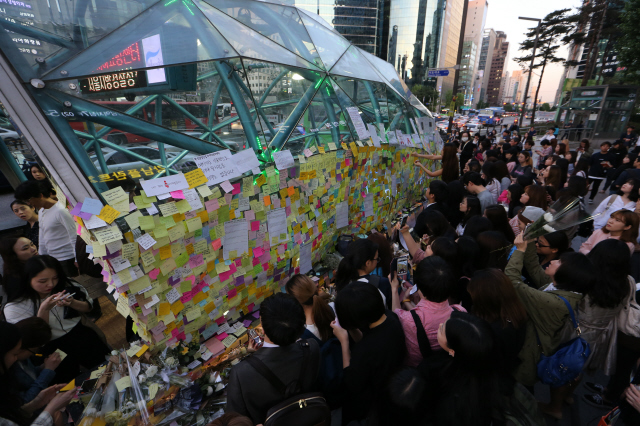 서울 강남역 인근 한 건물의 화장실에서 처음 보는 낯선 남성에게 살해당한 20대 여성을 추모하기 위해 시민들이 18일 오후 강남역 10번 출구에 추모글을 적은 포스트잇을 붙이고 국화꽃을 놓고 있다. 김정효 기자 hyopd@hani.co.kr