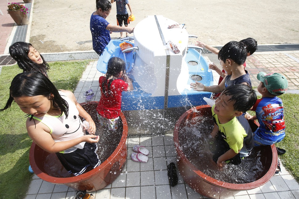 학교 수돗가에 대형 고무통이 놓이자 운동장 구석이 순식간에 워터파크로 변했다. 아이들이 뜨거운 태양 아래 물장난을 치고 있다.