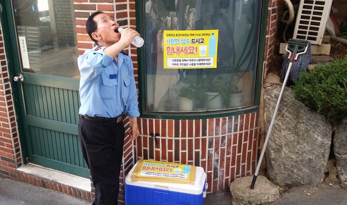 부산 부산진구 부암동의 럭키아파트의 경비원 오아무개(74)씨가 생수를 마시고 무더위를 식히고 있다. 아파트 주민 이재형(56)씨가 무더위에서 고생하는 이웃들을 위한 배려로 생수를 마련했다.
