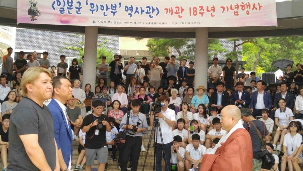 영화 <귀향>의 제작사 제이오엔터테이먼트코리아의 박현주·임성철 피디가 나눔의 집 원장 원행 스님에게 8·15 광복절을 맞아 출시된 ‘귀향’ 디브이디 특별판을 전달하고 있다. 뒷쪽 객석 중앙에서 박옥선·하점연·이옥선·안점순 할머니가 지켜보고 있다.