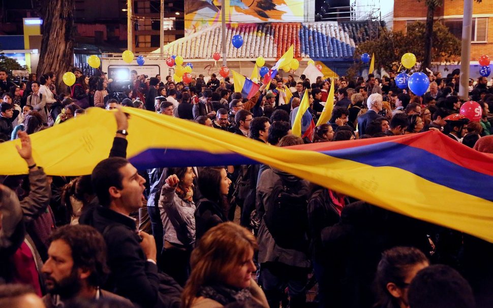 24일 쿠바의 수도 아바나에서 콜롬비아 정부와 콜롬비아무장혁명군(FARC) 사이의 평화협상이 최종 타결되는 장면을 방송으로 보던 콜롬비아의 수도 보고타의 시민들이 국기를 흔들며 기뻐하고 있다. 보고타/EPA 연합뉴스