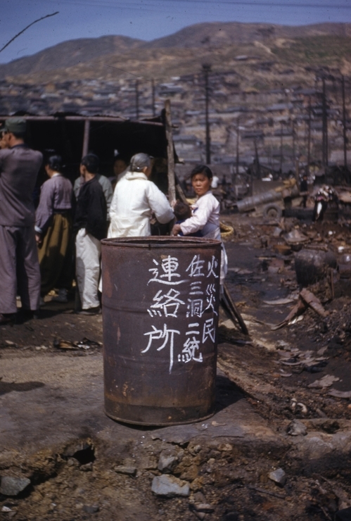 1952년 4월 화재가 난 부산 동구 증산마을 풍경. 화재민 연락소라고 적힌 드럼통 뒤로 사람들이 몰려 있다.