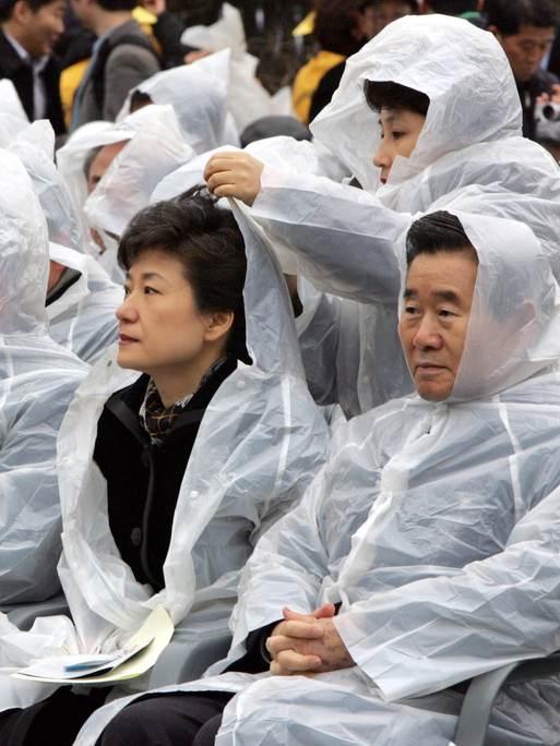 2005년 대구지하철 참사 희생자 추모식에서 한나라당 전여옥 대변인이 박근혜 대표의 비옷에 달린 모자를 씌워주고 있다. 사진 연합뉴스