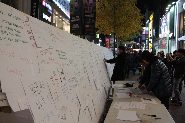 12일 저녁 8시 대구 중구 동성로 대구백화점 앞에서 사람들이 게시판에 붙일 글을 적고 있다.