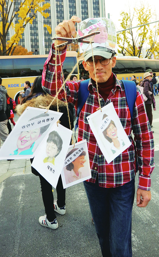 지난 12일 서울 광화문에서 열린 박근혜 퇴진 촉구 3차 촛불집회에서 한 시민이 꼭두각시를 들고 있다. 연합뉴스