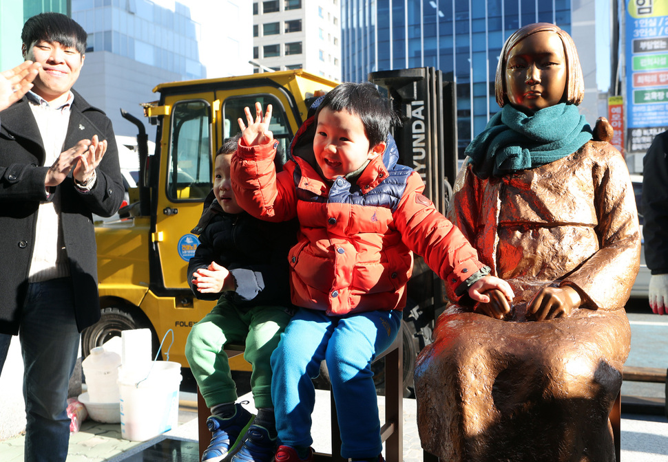 30일 부산 동구 초량동 일본 영사관 앞 인도에 ‘평화의 소녀상‘이 강제철거 이틀만에 다시 들어서자 어린이들이 소녀상 손을 잡고 사진을 찍고있다. 지난 28일 오후 부산 동구청은 ‘불법 노상 적치물’이란 이유로 시민들이 설치한 소녀상을 철거했다 거센 비판을 받았고, 이날 오전 압류한 소녀상을 돌려주고 일본영사관 앞 설치를 허용했다. 부산/연합뉴스