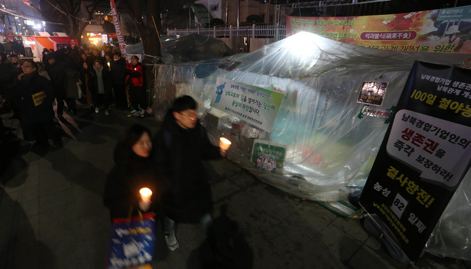 '끝까지 간다!9차 범국민행동-박근혜 정권 즉각 퇴진, 조기 탄핵, 적폐 청산 행동의 날' 집회가 열린 24일 저녁 서울 광화문 정부서울청사 앞 금강산기업인협의회와 남북경협기업비상대책위원회의 생존권보장 요구 천막농성장 옆을 촛불을 든 시민들이 지나가고 있다. 김정효 기자 hyopd@hani.co.kr