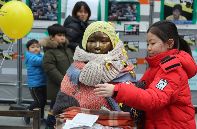 8일 서울 종로구 옛 일본대사관 앞에서 부모님과 함께 소녀상을 찾은 한 어린이가 동상을 포옹하고 있다. 연합뉴스