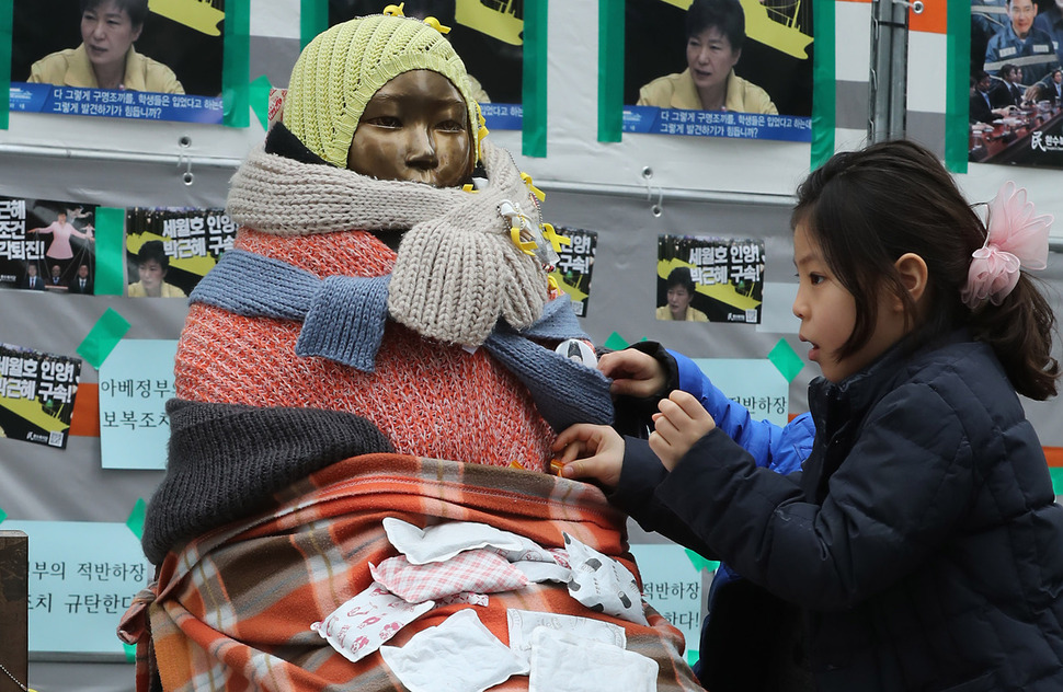 8일 서울 종로구 옛 일본대사관 앞에서 부모님과 함께 소녀상 동상을 찾은 한 어린이가 동상의 옷을 여며주고 있다. 아베 신조 일본 총리는 이날 방송된 <엔에치케이>(NHK) 프로그램 ‘일요토론’에 출연해 부산뿐 아니라 서울의 위안부 소녀상에 대해서도 “한국 쪽이 제대로 성의를 보여야 한다”고 말했다. 연합뉴스