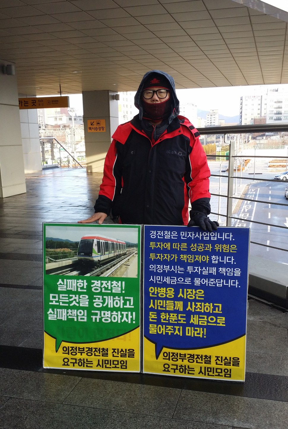 경기도 의정부지역 시민단체인 ‘의정부경전철 진실을 요구하는 시민모임’의 한 회원이 22일 의정부역 앞에서 의정부경전철 실패 책임 규명을 촉구하며 1인시위를 벌이고 있다.   ‘의정부경전철 시민모임’ 제공