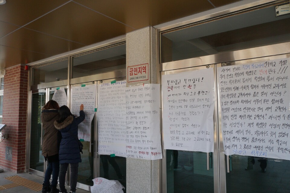 23일 오전 문명고 학부모들이 학교 현관 문에 국정 역사교과서 연구학교 지정 철회를 촉구하는 내용의 대자보를 붙이고 있다. 대구/김일우 기자