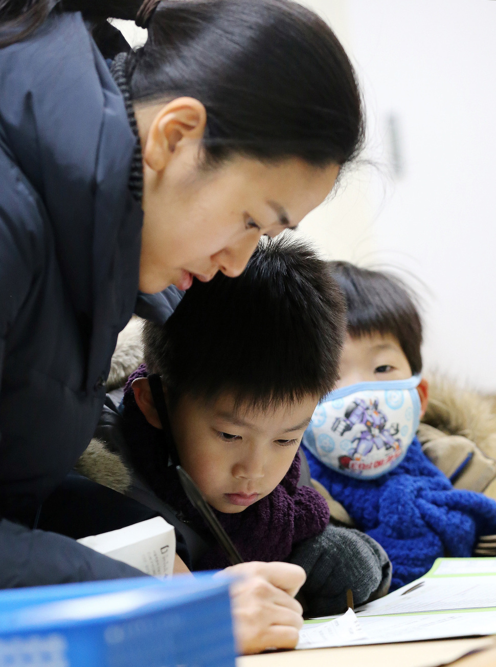 서울지역 초등학생 예비소집이 열린 1월11일 오후 서울 염리초등학교에서 엄아와 동생과 함께 참석한 예비초등학생이 엄마의 서류작성을 바라보고 있다. 김경호 선임기자 jijae@hani.co.kr