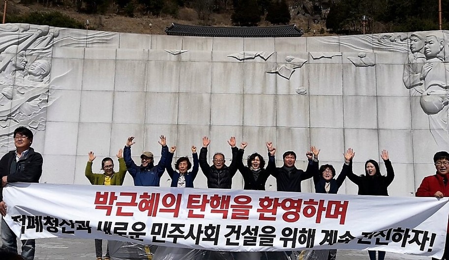 경남 창원시민들이 10일 국립3·15민주묘지 들머리에서 박근혜 전 대통령 탄핵을 환영하는 만세를 외치고 있다.