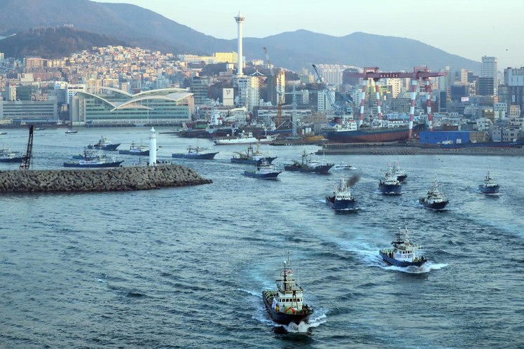 지난달 15일 부산 남항에서 선망 어선 100여 척이 바닷모래 채취를 반대하는 현수막을 걸고 출항하고 있다. <연합뉴스>