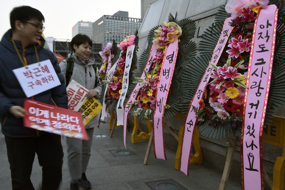 ‘염병하네!’, ‘아직도 그 사람 거기 있나요’, ‘참 나쁜 여자예요’…. 혹한의 겨울을 이겨내고 천만 촛불을 밝혔던 서울 광화문광장의 세종대왕 동상 곁에 박근혜 전 대통령의 파면을 축하하는 화환들이 봄처럼 환히 줄 서 있다. ‘기쁘다 박근혜 파면’, ‘이게 나라다 이게 정의다’, ‘국민이 주인이다’, ‘적폐청산 공정국가’, ‘세월호 인양 미수습자 수습’…. 화환에 달린 리본 글에는 촛불 시민들의 다양한 마음이 달려 있다. 파면된 민간인 신분의 박근혜 전 대통령은 21일 검찰 출두를 앞두고 있다. 이번에는 검찰 조사에 정말 성실히 임하려는지 모르겠다. 박근혜를 구속하라! 강재훈 선임기자 khan@hani.co.kr