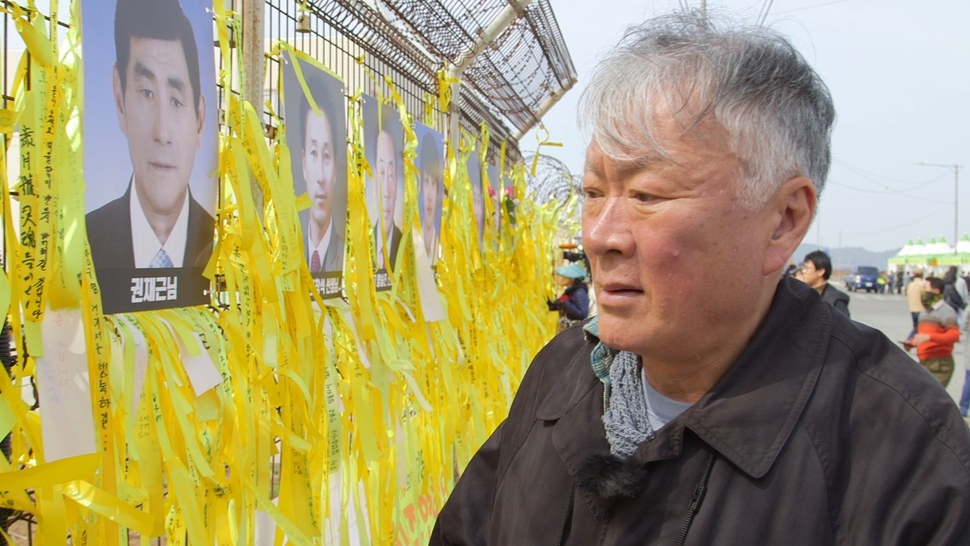 세월호 희생자 추모 리본을 바라보고 있는 김훈 작가. <한국방송> 제공