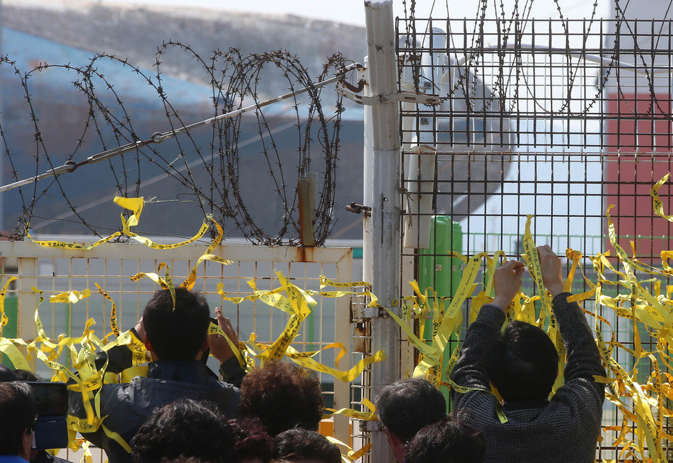 1일 오후 전남 목포시 목포신항에 도착한 세월호의 모습을 보기 위해 모인 시민들이 철재부두 펜스에 노란 리본을 달고 있다. 목포/신소영 기자 viator@hani.co.kr