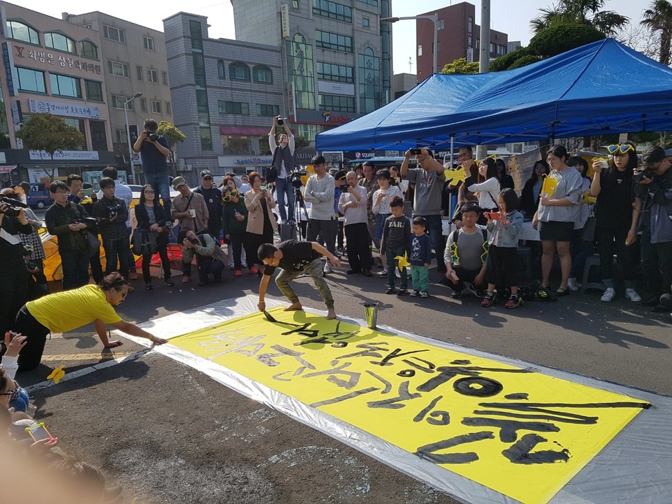 16일 오후 제주시청 앞에서 열린 추모행사에서 신동욱 작가가 ‘꽃이 진다고 그대를 잊은 적 없다’는 붓글씨를 스고 있다.