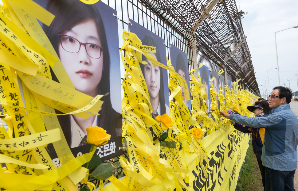 세월호 참사 3주기를 이틀 앞둔 14일 오후 전남 목포신항을 찾은 추모객들이 철재부두 외각 철조망에 노랑리본을 묶고 있다. 공동취재사진