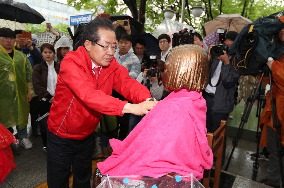 홍준표 자유한국당 대통령 후보가 17일 오후 대구 2.28 기념 중앙공원에 설치된 ‘평화의 소녀상’을 찾아 빗물을 닦아내고 있다. 대구/연합뉴스