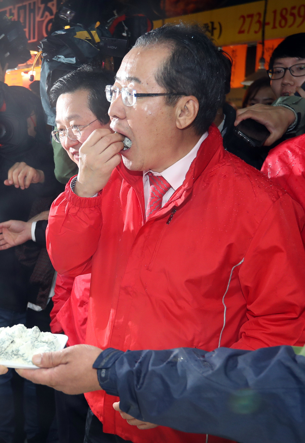 자유한국당 홍준표 대선후보가 17일 오전 대전역 앞 전통시장에서 상인들에게 지지를 호소한 후 한 상인이 건넨 떡을 먹고 있다. 연합뉴스