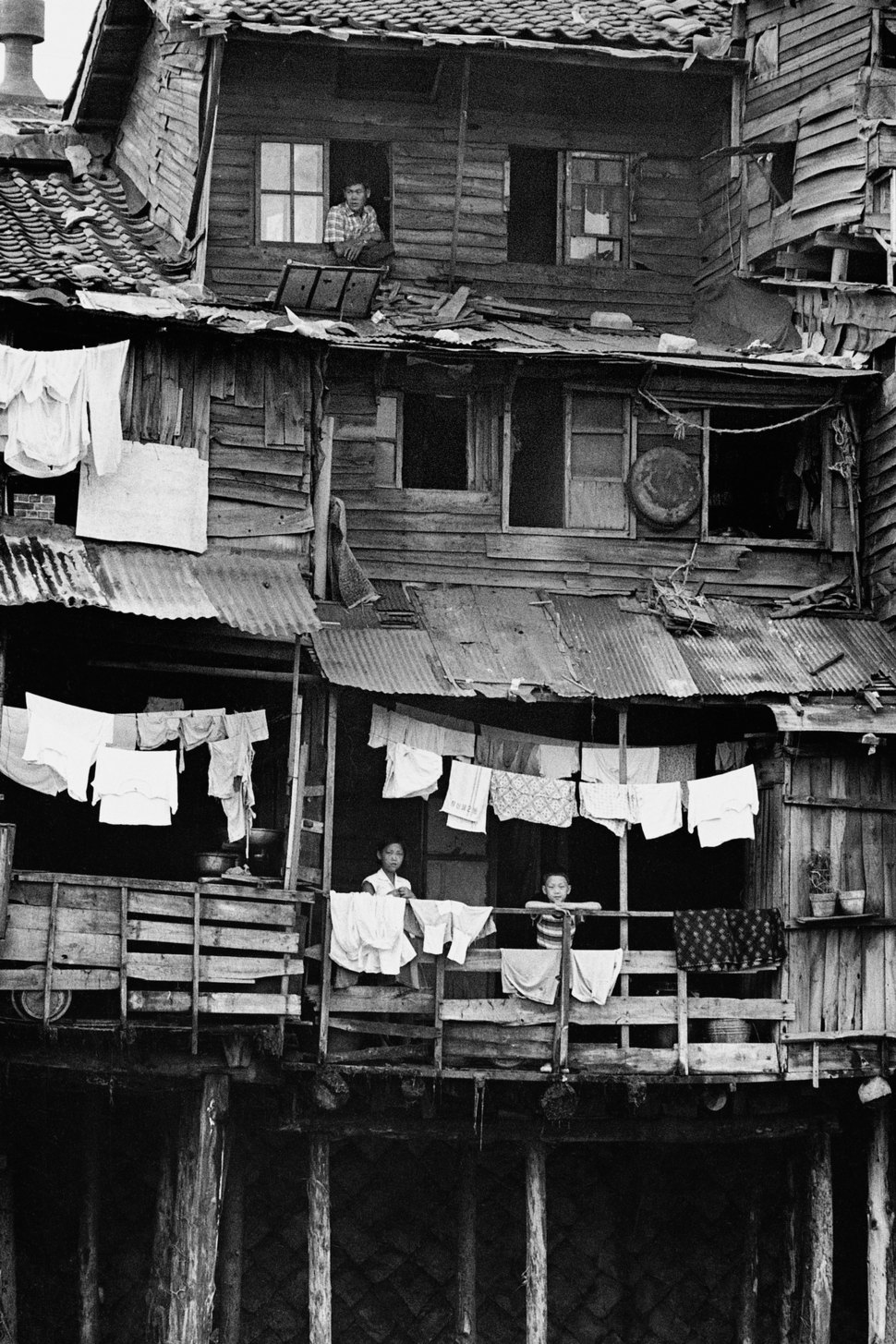 1965년 청계천가 판잣집에 사는 사람들이 발코니와 창을 통해 밖을 바라보고 있다. 서울시
