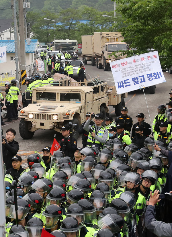 26일 오전 경북 성주군 성주골프장으로 사드(THAAD·고고도미사일방어) 체계 관련 장비를 실은 트레일러가 들어가자 사드 배치를 반대하는 성주군 주민 등이 경찰 병력 뒤편에서 사드 반대 펼침막을 들고 있다. 성주/연합뉴스