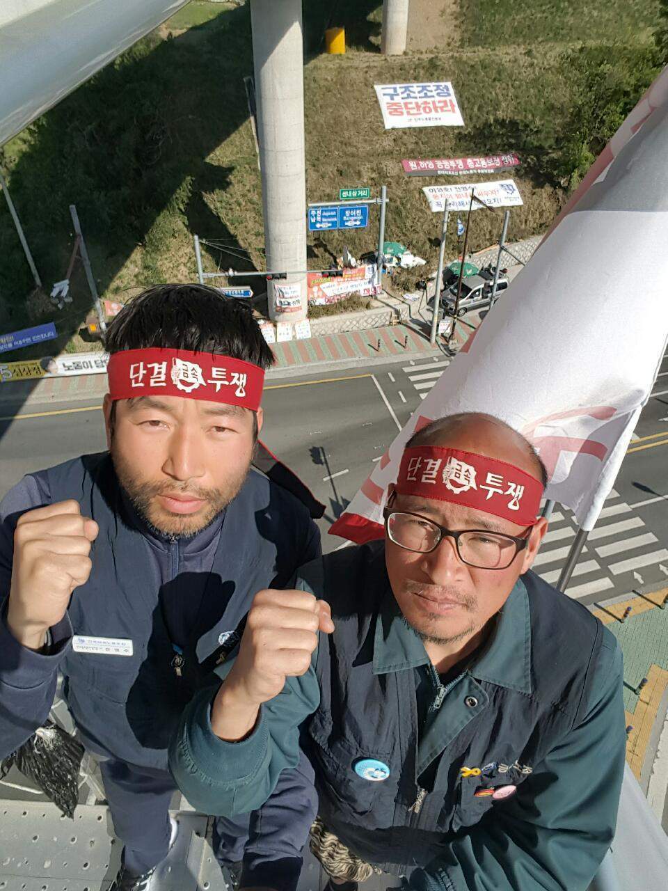 전영수·이성호씨(왼쪽부터)의 고공농성장 밑으로 도로와 이들을 응원하는 펼침막 등이 보인다. 전영수·이성호씨 제공