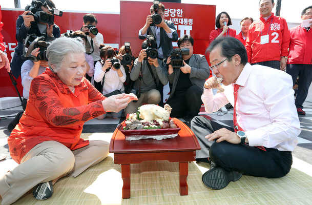 홍준표 자유한국당 대통령 후보(오른쪽)가 1일 오후 전주 전동성당 인근에서 열린 유세에서 지지자로부터 씨암탉을 선물 받아 먹고 있다. 홍 후보의 부인 이순삼씨가 전북 부안 출신이다. 전주/연합뉴스