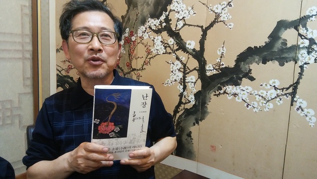 신작 소설 <난장>을 들고 카메라 앞에 선 홍성담 작가. “마당극 같은 글놀음으로 세월호 영령의 한을 풀어내리는 놀이를 펼친 것”이라고 말했다.